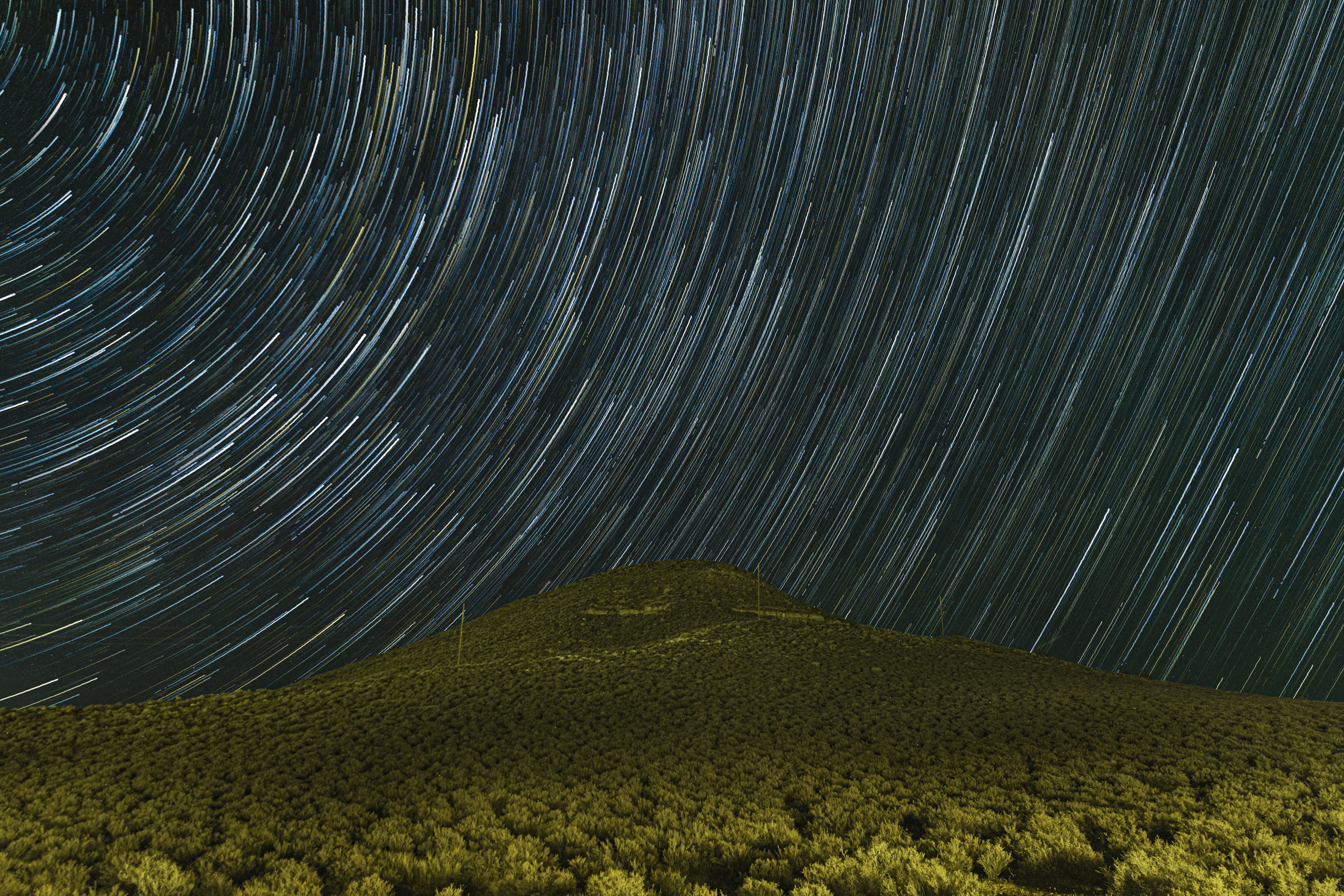 Star trails over a desert hill